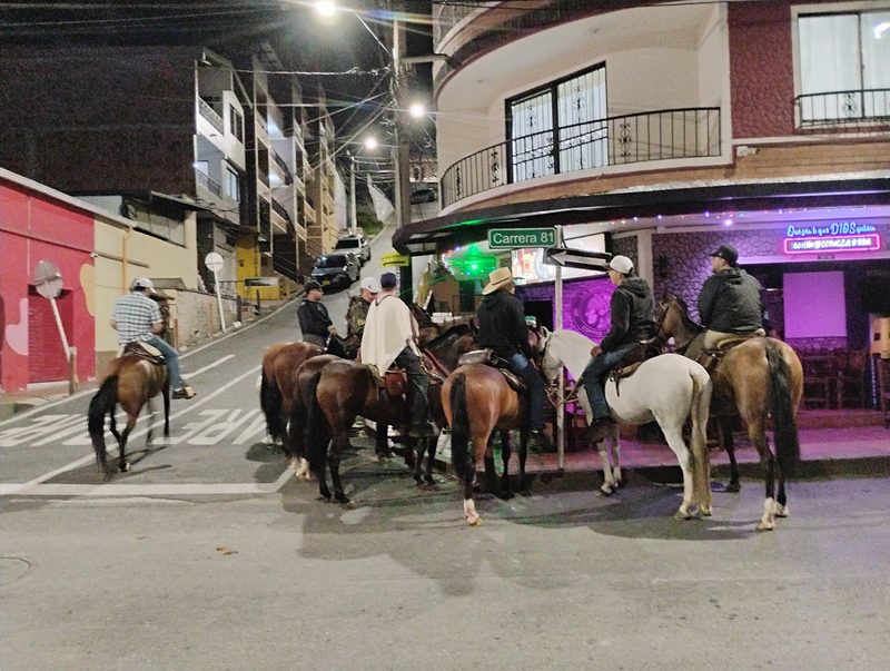 Jinetes a caballo detenidos de noche en una esquina del pueblo.