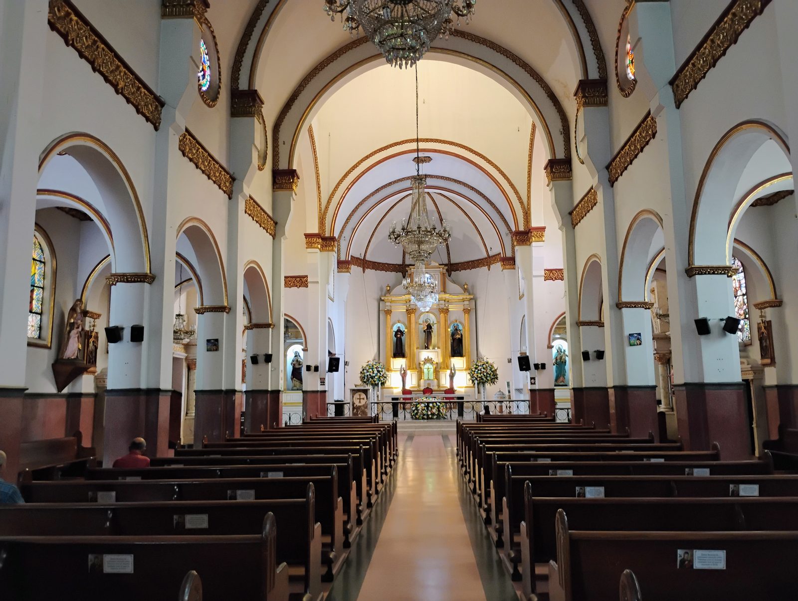 Nave central del templo con arquer&iacute;a dorada y ara&ntilde;as de cristal.